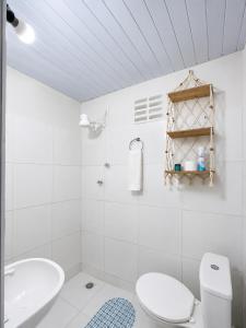 a white bathroom with a toilet and a sink at Chalé Rosani in Pipa