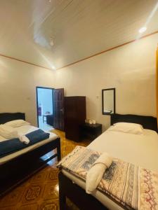 a bedroom with two beds and a mirror at Mawar Bed and Breakfast in Bajawa