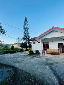 a white building with a bench in a parking lot at Mawar Bed and Breakfast in Bajawa