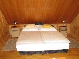 Cama en habitación de madera con 2 mesitas de noche en Ottó Nyaraló en Révfülöp