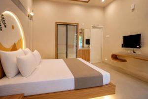 a bedroom with a large bed and a television at Ayana Lake Resorts in Kovillūr