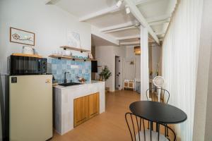 a kitchen with a white refrigerator and a table at Sea Salt Stay Samui in Nathon