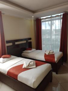 a bedroom with two beds with red curtains and a window at Claire de Lune Moonlight Hotel in Nakuru +52 photos