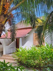 a white house with a red roof and some palm trees at Serah's Homestay in Kuta Lombok