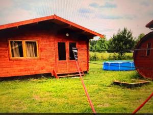 a small red house in a field with a yard at Eco domki Mazury in Ruciane-Nida +3 photos