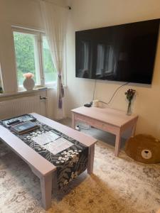 a living room with a table and a large flat screen tv at Karhulan Kammari, oma sisäänkäynti ja WC, Valkeakoski keskusta in Valkeakoski