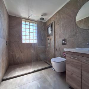 a bathroom with a shower and a toilet and a sink at Kipos Suites Nidri Lefkada in Nydri