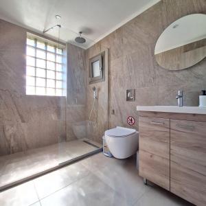a bathroom with a shower and a toilet and a sink at Kipos Suites Nidri Lefkada in Nydri +89 photos