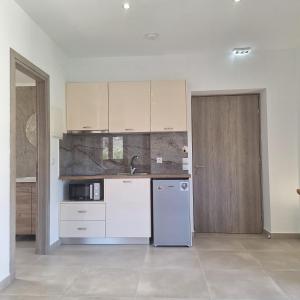 a kitchen with white cabinets and a refrigerator at Kipos Suites Nidri Lefkada in Nydri