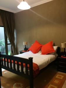 a bedroom with a bed with red pillows and a window at Hilken Lodge in Durban
