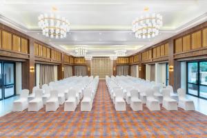 a conference room with white chairs and tables and chandeliers at Siddhartha Riverside Resort, Chumlingtar in Makaising