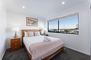 un dormitorio con una cama y una ventana grande en Homenest, en Gledswood Hills