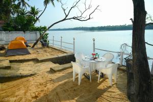 a table and chairs sitting next to the water at Sattva camps and cottages - Udupi in Udupi