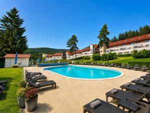 a swimming pool with lounge chairs and a resort at SNOW LAKE Lipno in Lipno nad Vltavou