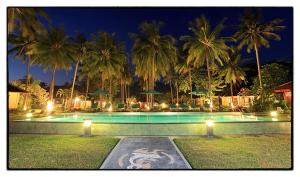 a swimming pool with palm trees at night at mascot hotel senggigi in Senggigi