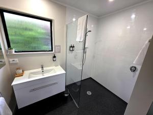 a white bathroom with a shower and a sink at Arran Motel in Te Anau