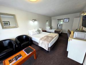 a hotel room with a bed and a desk and a tv at Arran Motel in Te Anau