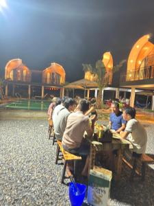 a group of people sitting at a table in front of a building at Green Valley Retreat in Phong Nha