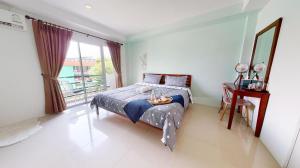 a bedroom with a bed and a table and a window at RungRoj Panich Hotel in Ban Bang Saen (1)