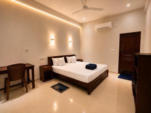 a bedroom with a bed and a table and a desk at Blue Wings Arugam Bay in Arugam Bay