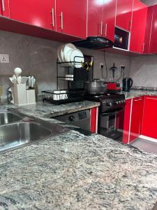 a kitchen with red cabinets and a granite counter top at Grey Ivy Apartment in Abuja