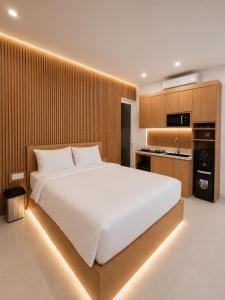a bedroom with a large white bed and a kitchen at Hotel K Seminyak in Badung