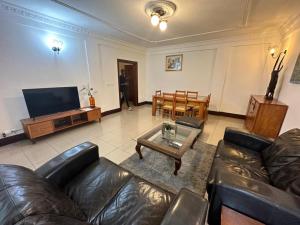 a living room with a leather couch and a table at Résidence shalismi in Yaoundé