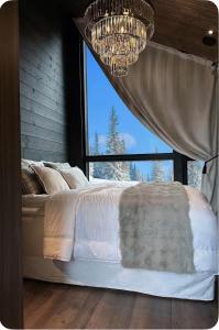 a bedroom with a bed with a window and a chandelier at Villa Blackreindeer in Kolari