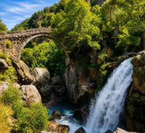 a waterfall under a stone bridge over a river at Casa Misarela in Ruivãis