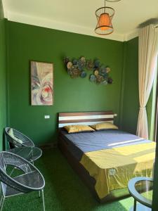 a bedroom with a bed with green walls and chairs at She Stay in Hòa Bình
