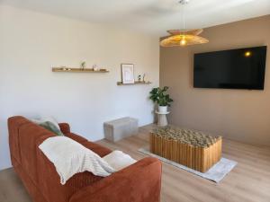 a living room with a couch and a flat screen tv at L'Escale Cosy avec Terasse in Noidans-lès-Vesoul