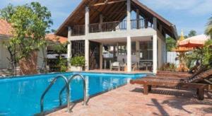 a house with a swimming pool next to a building at Lotusland Resort in Jomtien Beach
