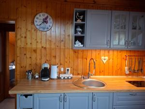 a kitchen with a sink and a clock on the wall at Chata Bobo in Stožok