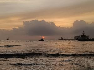 a boat in the ocean with a sunset in the background at Hope Hostels, Fort Kochi in Fort Kochi