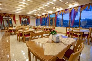a restaurant with tables and chairs and large windows at Nairi Hotel in Jermuk