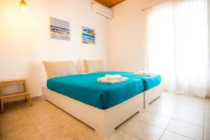 a bedroom with a large bed with blue sheets at Serenity Apartments, Next to the Beach in Agios Georgios