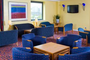a waiting room with blue chairs and tables and a tv at Holiday Inn Express Bradford City Centre by IHG in Bradford