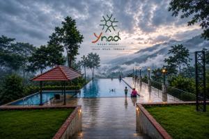 a pool in the rain with people walking around it at Ynad Mount Resort in Meppādi