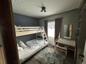 a bedroom with bunk beds and a desk and a window at Fishermans luck in Arvidsjaur