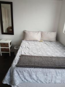 a bed with white sheets and a mirror in a room at Jacqui's abode in Kirstenhof
