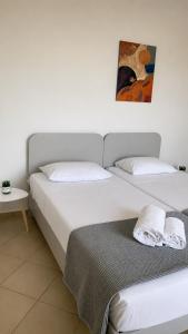 a bedroom with two beds and a painting on the wall at Velmare apartments in Paralia Vrachou