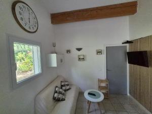 a living room with a couch and a clock on the wall at Mazet sous les chênes in Valaurie