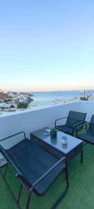 three chairs and a table on a balcony with the ocean at Saris rooms in Pera Gyalos