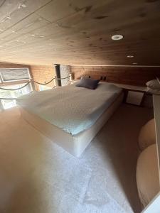 a bed in a room with a wooden ceiling at Skogsviken Guesthouse in Munkedal