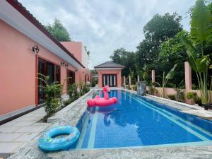 a swimming pool with a pink house and a red float in the water at Mori Khem Beach Homestay in Phú Quốc