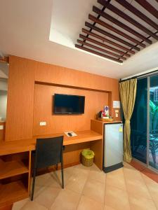 a room with a desk and a television on a wall at PorterHouse Beach Hotel in Patong Beach