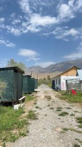 a dirt road next to a building with mountains in the background at ЭКО балык Седеп юурт 