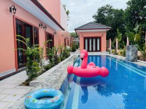 a swimming pool with a pink house and a red float at Mori Khem Beach Homestay in Phú Quốc +10 photos