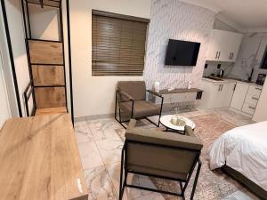 a room with a bed and a table and a kitchen at The Benjamin Guest House in Edenvale