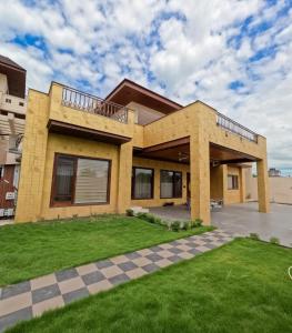 a large yellow house with a balcony at Sukuun Villa Airport Road #Luxury Pool Stay in Sri Guru Ram Dass Jee International Airport